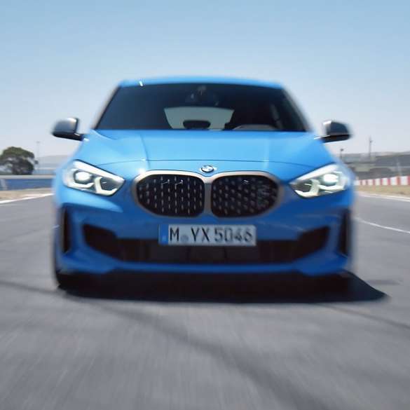 1er BMW Dreiviertel Frontschuss am Straßenrand. 1er BMW in Misano Blau metallic, Dreiviertel-Frontansicht am Straßenrand parkend.