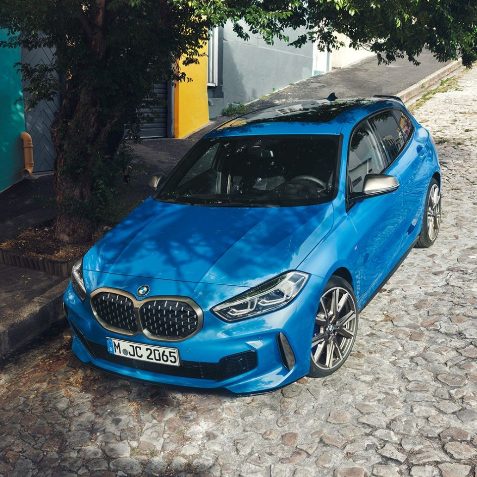 1er BMW am Straßenrand. 1er BMW in Misano Blau metallic, Dreiviertel-Frontansicht am Straßenrand parkend aus der Vogelperspektive.