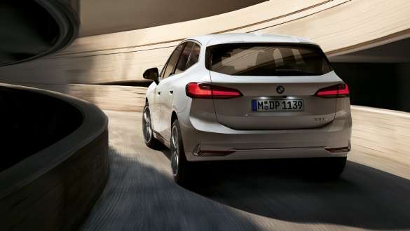 Dynamisches Heckdesign BMW 2er Active Tourer U06 2021 BMW 2er Active Tourer U06 2021 Mineralweiß metallic Heckansicht beim Hinauffahren der Wendelrampe im Parkhaus