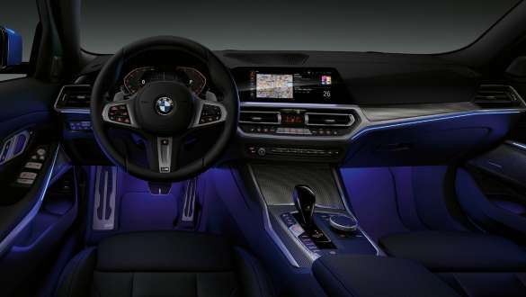 BMW 3er Limousine, Ambientes Licht. Frontaufnahme des fahrerseitigen Cockpits der BMW 3er Limousine mit blau beleuchtetem Fussraum durch ambientes Licht.