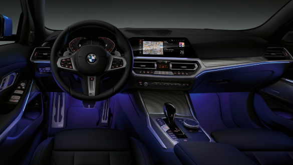 BMW 3er Limousine, Ambientes Licht. Frontaufnahme des fahrerseitigen Cockpits der BMW 3er Limousine mit blau beleuchtetem Fussraum durch ambientes Licht.
