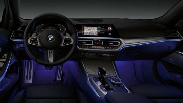 BMW 3er Limousine (G20), Ambientes Licht. Frontaufnahme des fahrerseitigen Cockpits der BMW 3er Limousine (G20) mit blau beleuchtetem Fussraum durch ambientes Licht.