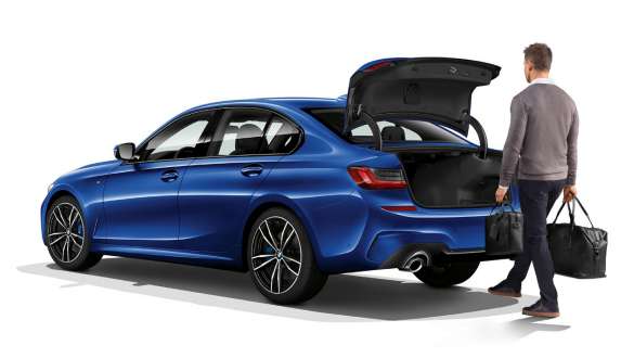 BMW 3er Limousine (G20), automatische Heckklappenbetätigung. Dreiviertel Heckschuss der stehenden BMW 3er Limousine (G20) mit Fahrer, der mit dem Fuss automatisch die Heckklappe öffnet.