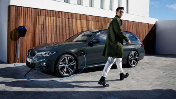 Plug-In Hybrid BMW 3er Touring 2021 G21 Dreiviertel-Seitenansicht an BMW Wallbox Plug-In Hybrid BMW 3er Touring 2021 G21 Dreiviertel-Seitenansicht an BMW Wallbox mit Model
