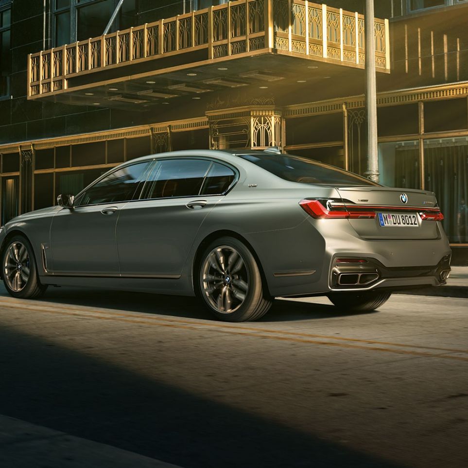 BMW M760Li xDrive mit V12-Motor BMW M760Li xDrive steht in seitlicher Heckansicht vor Wolkenkratzern in urbaner Kulisse