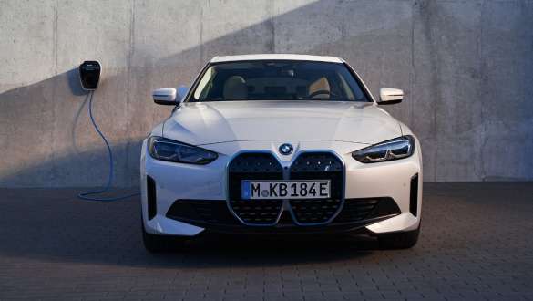 Frontansicht mit BMW Wallbox BMW i4 eDrive40 G26 2021 BMW i4 eDrive40 G26 2021 Mineralweiß Frontansicht vor Hauswand mit BMW Wallbox Ladestation