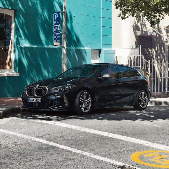 BMW M135i xDrive, Dreiviertel-Seitenansicht. BMW M135i xDrive in Saphirschwarz metallic, Dreiviertel-Seitenansicht parkend.