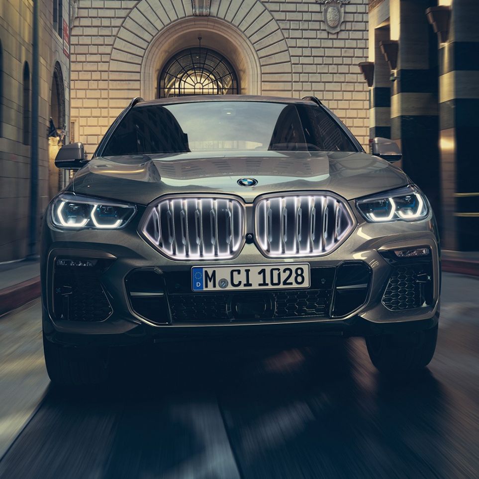 BMW X6 mit BMW Niere ‘Iconic Glow’. BMW X6 in Frontansicht vor urbaner Kulisse.