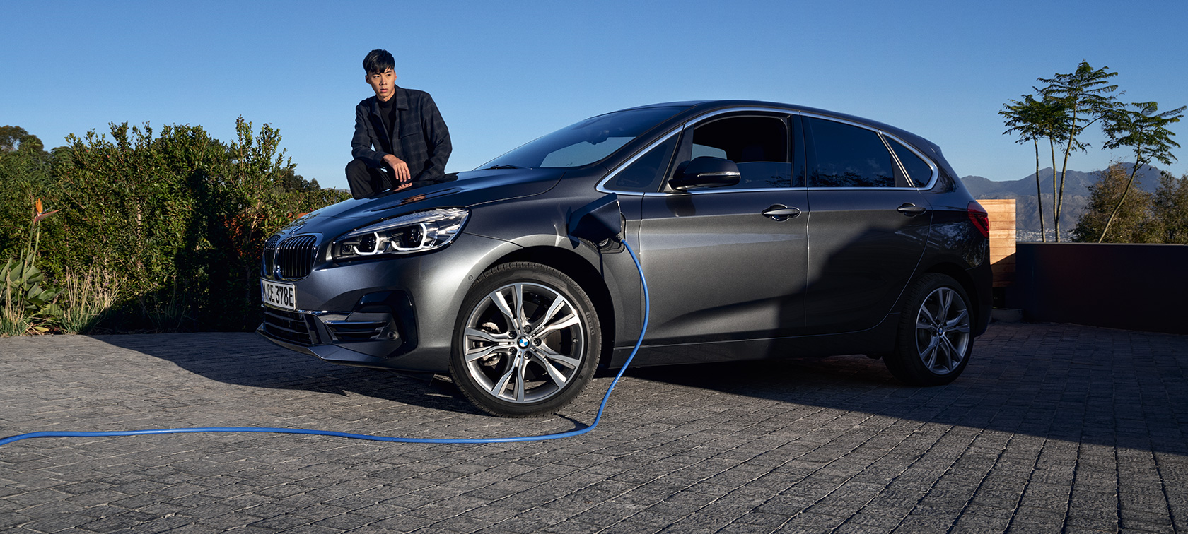 Plug-In Hybrid BMW 225xe Active Tourer F45 Dreiviertel-Seitenansicht ladend Plug-In Hybrid BMW 225xe Active Tourer F45 Dreiviertel-Seitenansicht ladend mit Model