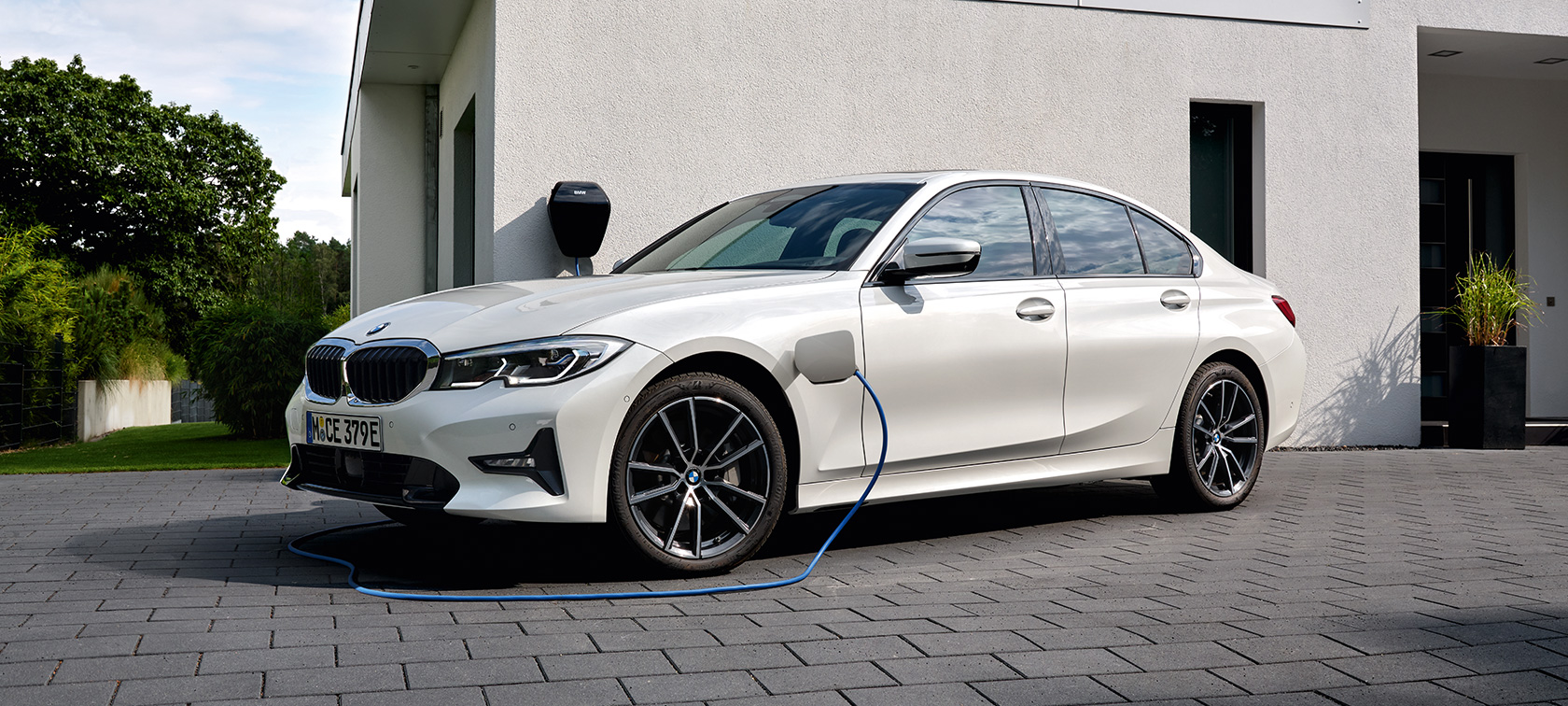 Plug-in Hybrid BMW 3er Limousine 2021 G20 G20 Dreiviertel-Seitenansicht ladend Plug-in Hybrid BMW 3er Limousine 2021 G20 Dreiviertel-Seitenansicht ladend vor Garage