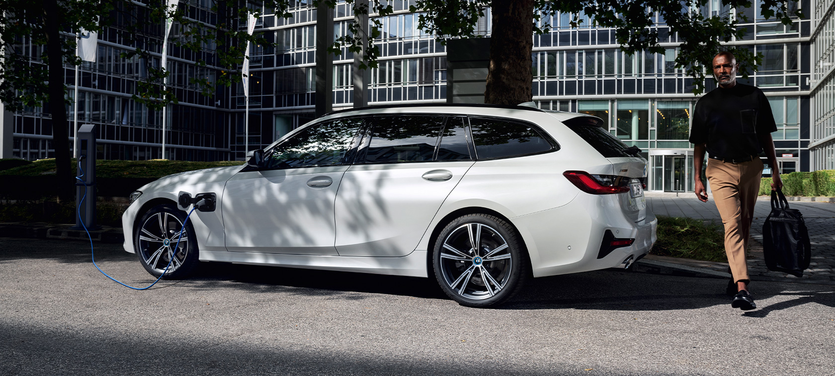 Plug-In Hybrid BMW 3er Touring 2021 G21 Dreiviertel-Seitenansicht ladend Plug-In Hybrid BMW 3er Touring 2021 G21 Dreiviertel-Seitenansicht ladend mit Model