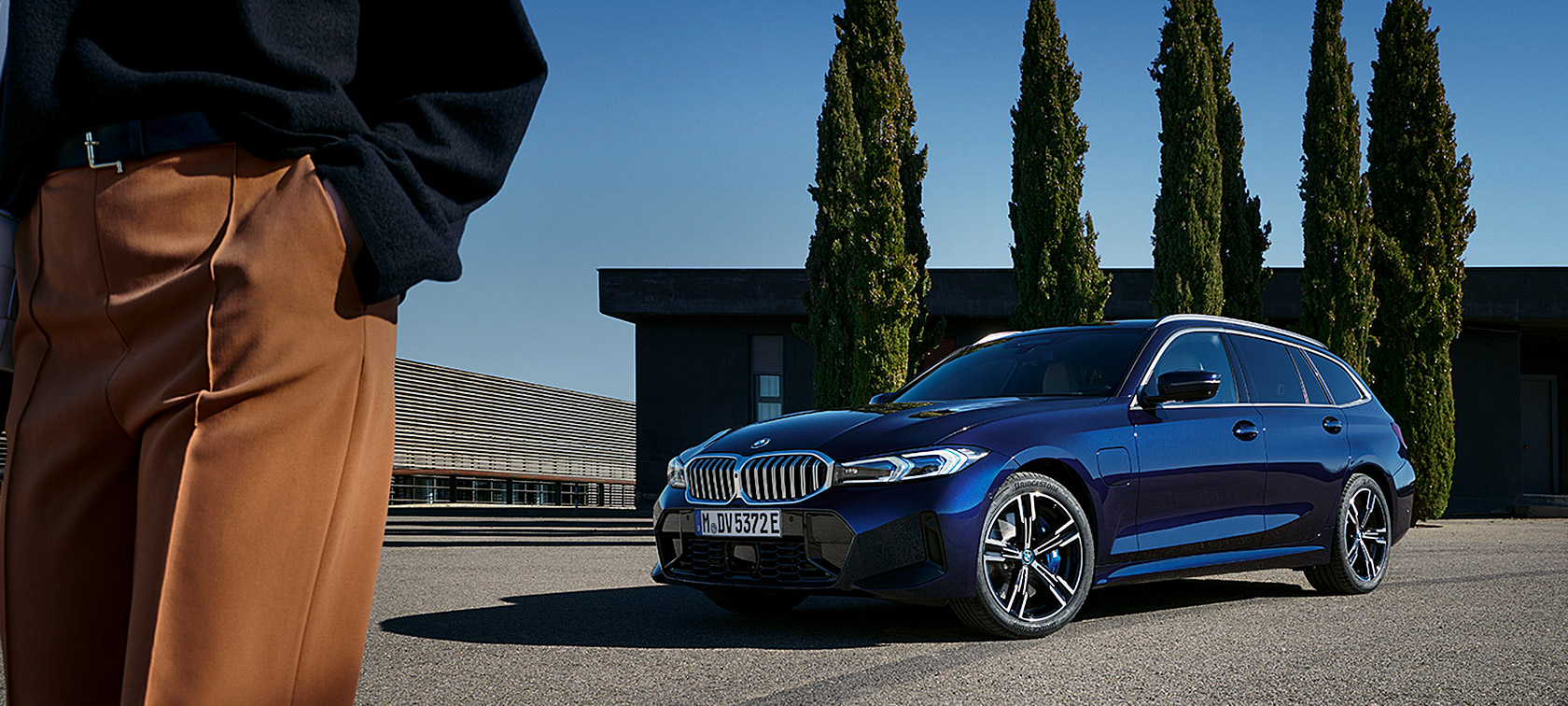 BMW 3er Touring LCI G21 Tansanitblau II Dreiviertel-Frontansicht stehend vor Bäumen