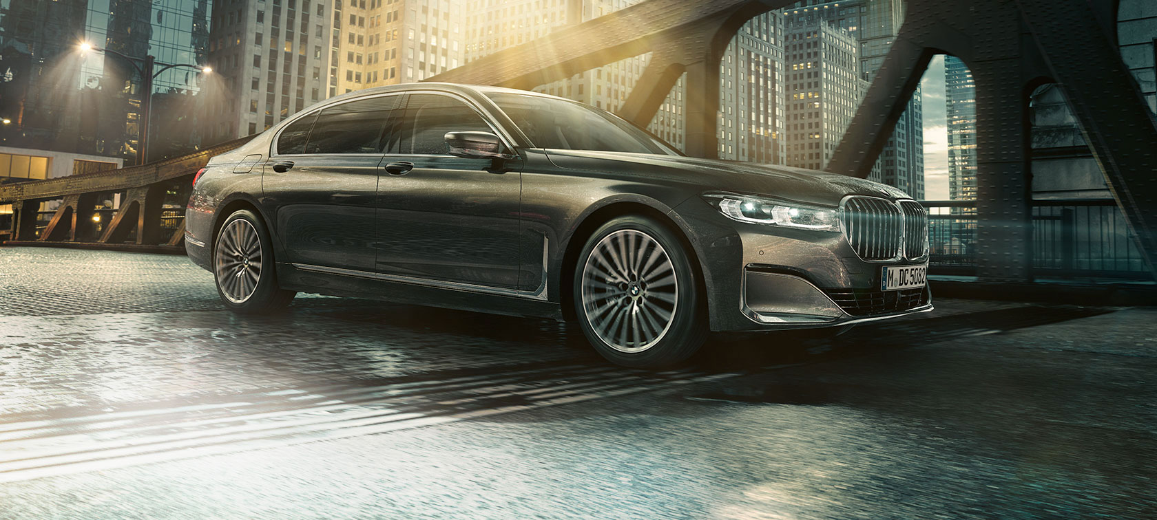 BMW 7er Limousine, Seitenansicht BMW 7er Limousine steht in der Seitenansicht mit geöffneter Tür vor beleuchtetem Hotel