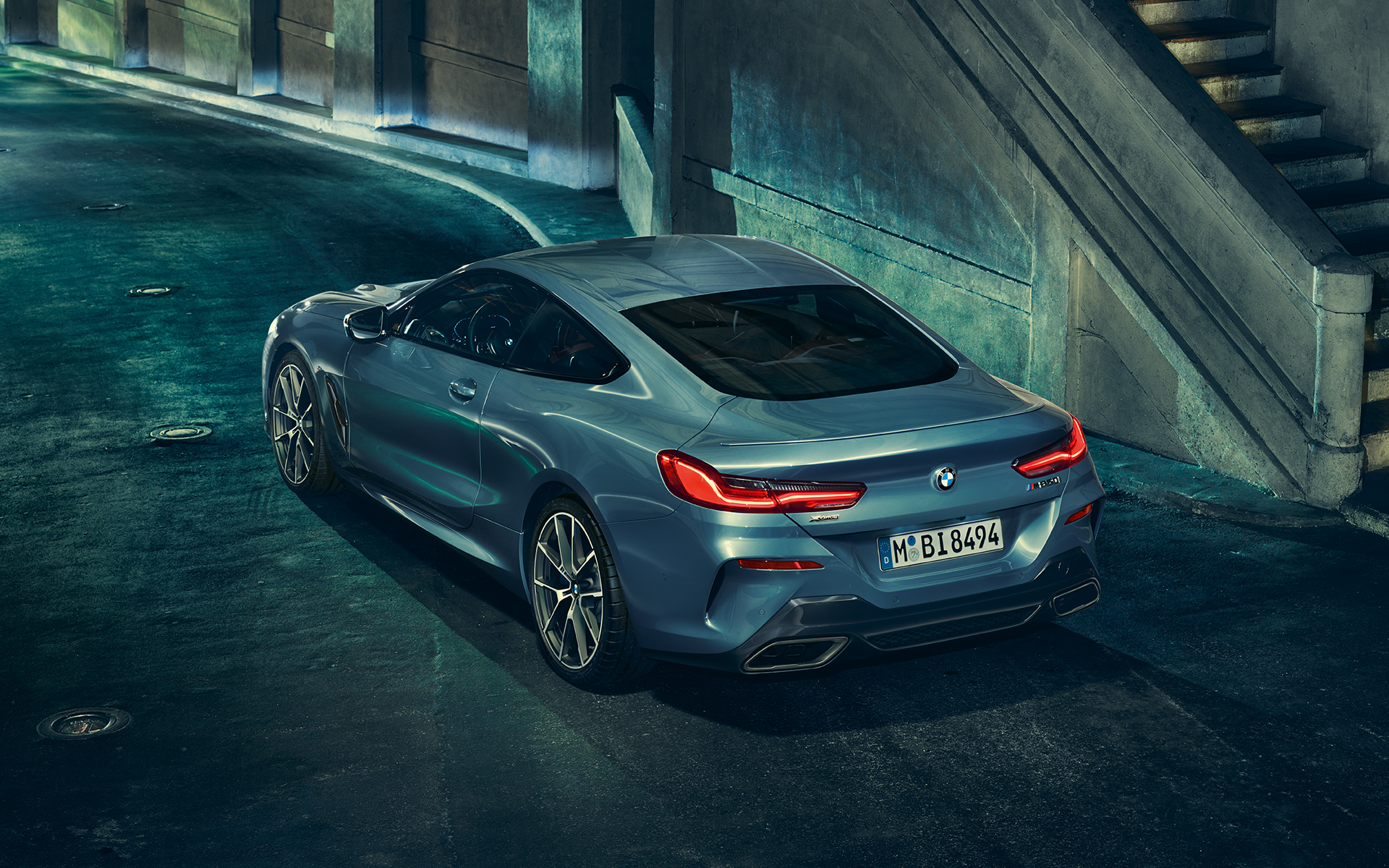 BMW 8er Coupé, Dreiviertel-Heck Linke Dreiviertel-Heck-Standaufnahme des BMW 8er Coupé in urbaner Kulisse.
