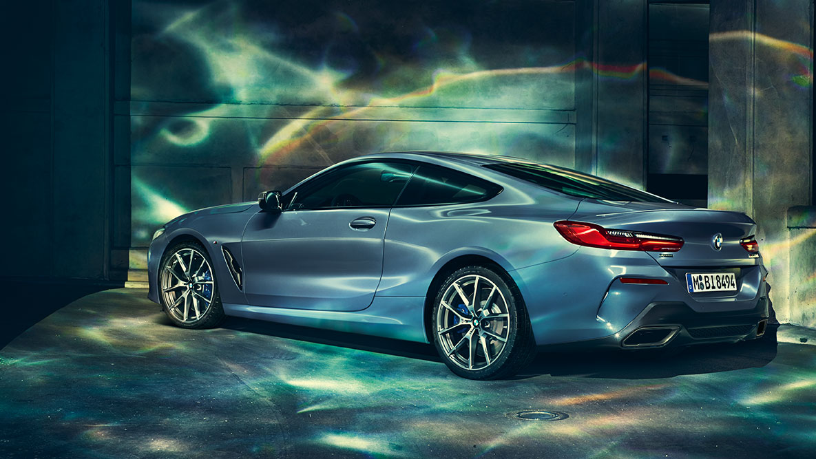 BMW 8er Coupé, Dreiviertel-Heckschuss. Dreiviertel-Heckschuss des BMW 8er Coupé in der Nacht vor urbaner Kulisse.