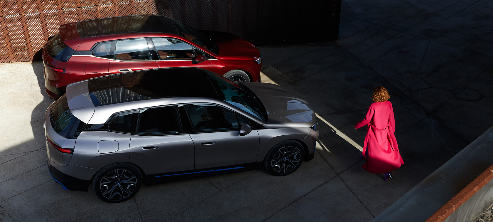 BMW iX Vogelperspektive mit Model BMW iX Aventurinrot und Kaschmirsilber i20 Vogelperspektive mit Model