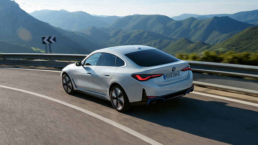 Dreiviertel-Heckansicht BMW i4 eDrive40 G26 2021 fahrend BMW i4 eDrive40 G26 2021 Mineralweiß Dreiviertel-Heckansicht fahrend