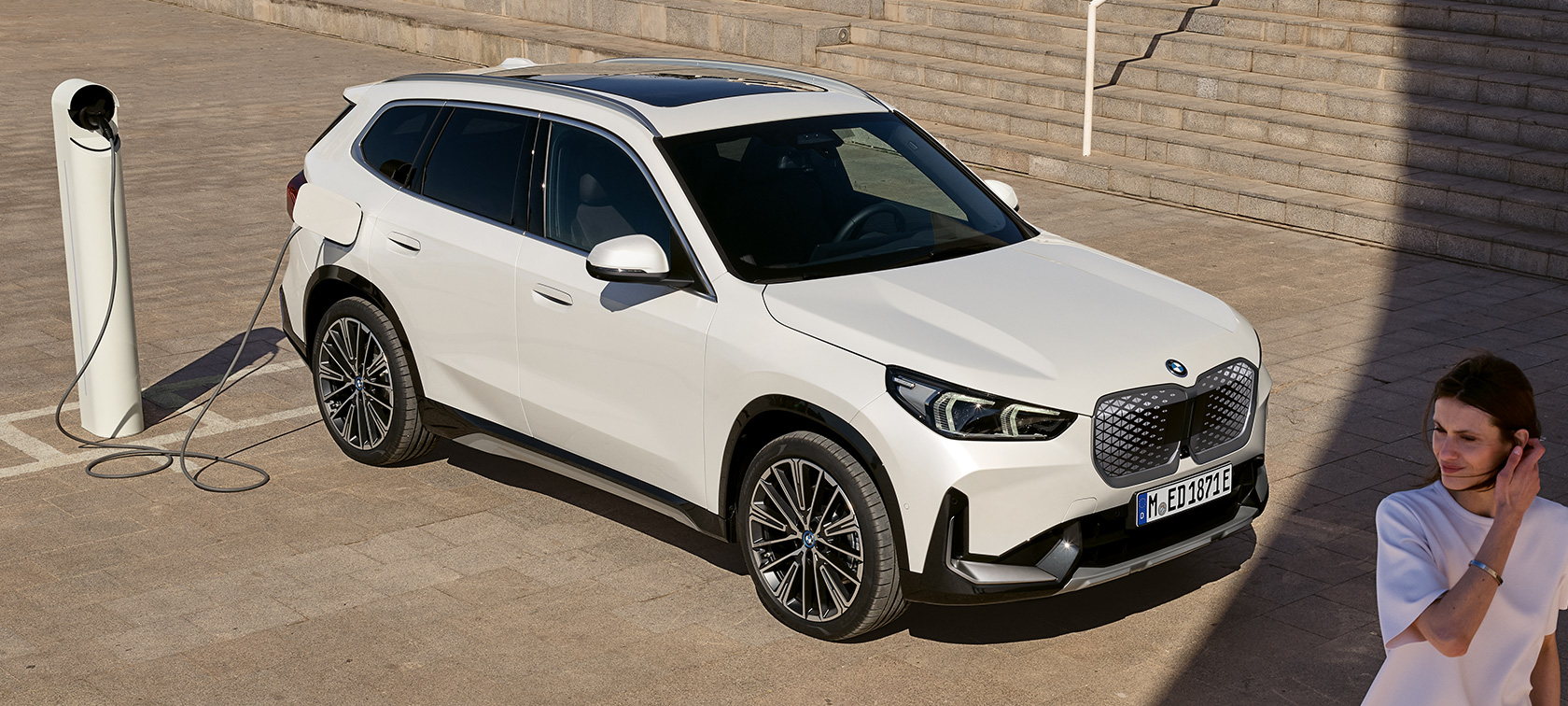 BMW iX1 U11 BEV Seitenansicht ladend BMW iX1 U11 BEV 2022 Mineralweiß metallic Zwei drittel Seitenansicht ladend Treppen