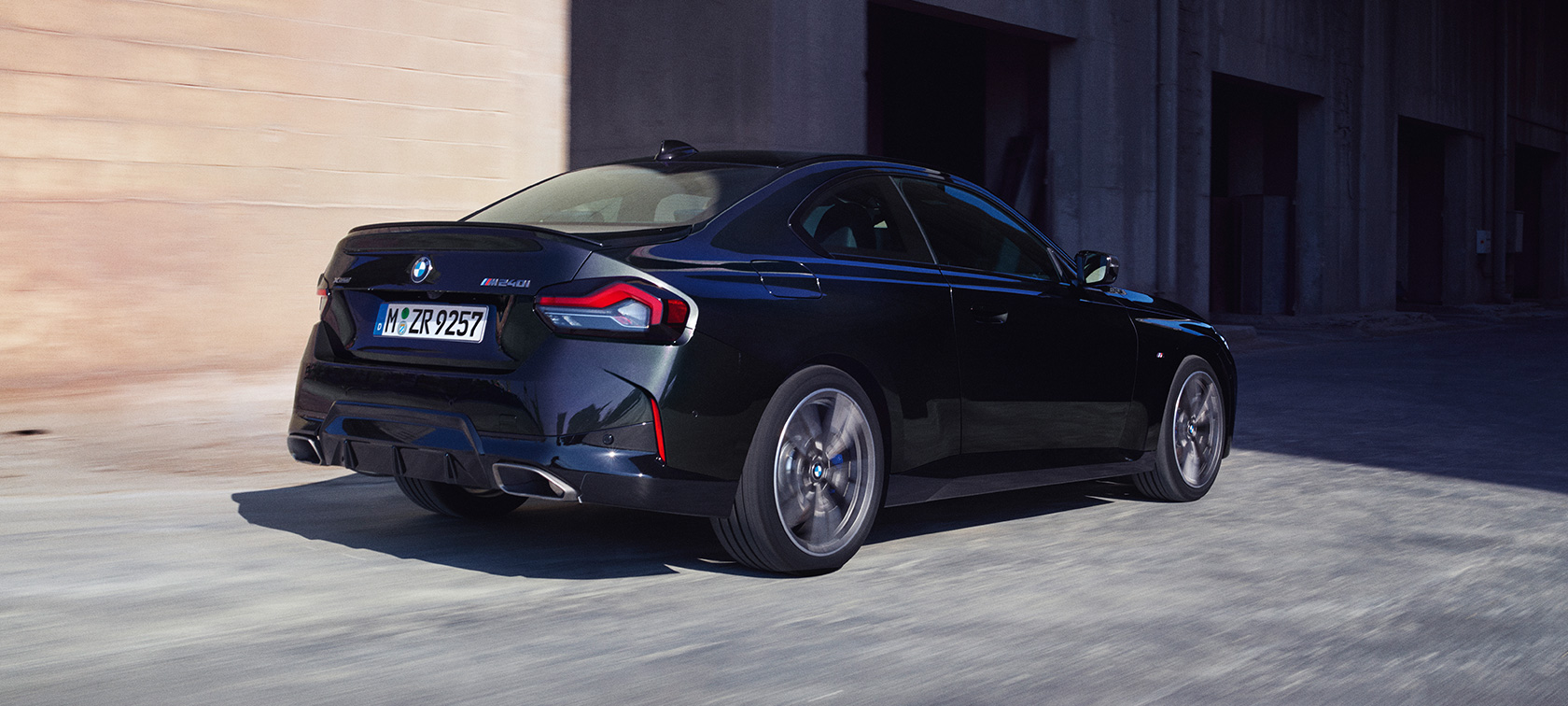 Dreiviertel-Heckansicht BMW M240i xDrive Coupé G42 2021 BMW M240i xDrive Coupé G42 2021 Black Sapphire metallic Dreiviertel-Heckansicht fahrend