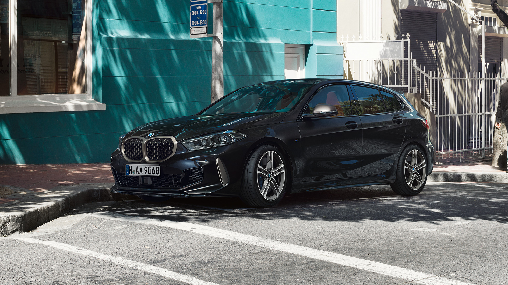 BMW M135i xDrive, Dreiviertel-Seitenansicht. BMW M135i xDrive in Saphirschwarz metallic, Dreiviertel-Seitenansicht parkend.