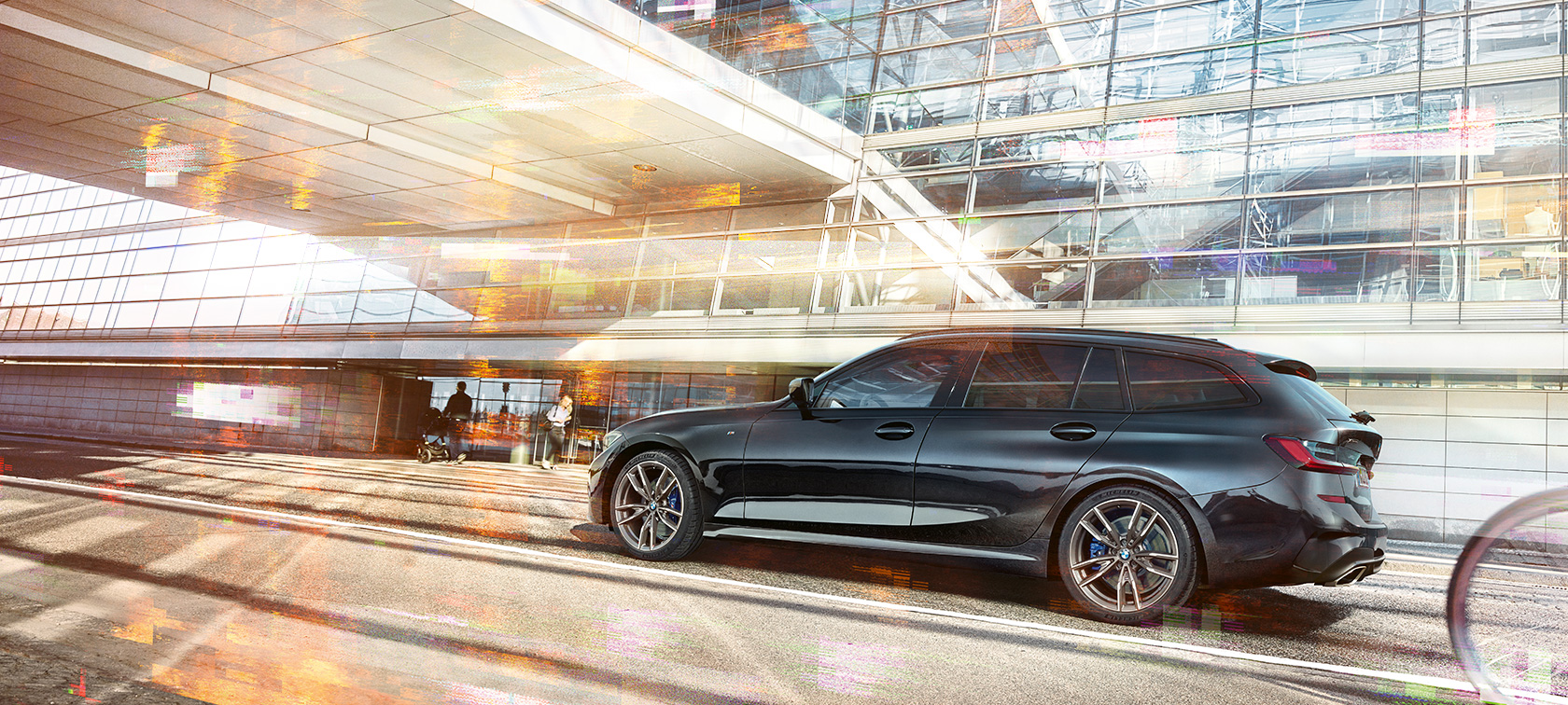 BMW M340i xDrive Touring, seitliche Fahraufnahme BMW M340i xDrive Touring, seitliche Fahraufnahme vor urbanem Glasgebäude