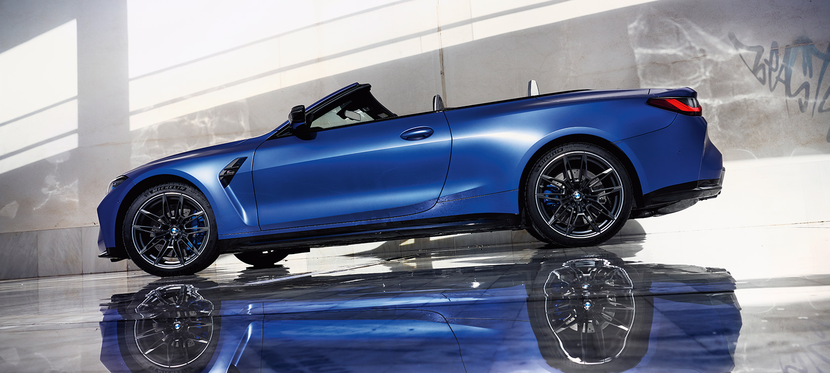 BMW M4 Competition Cabrio mit M xDrive G83 2021 Dreiviertel-Frontansicht fahrend BMW M4 Competition Cabrio mit M xDrive G83 2021 BMW Individual Frozen Portimao Blau metallic Dreiviertel-Frontansicht fahrend