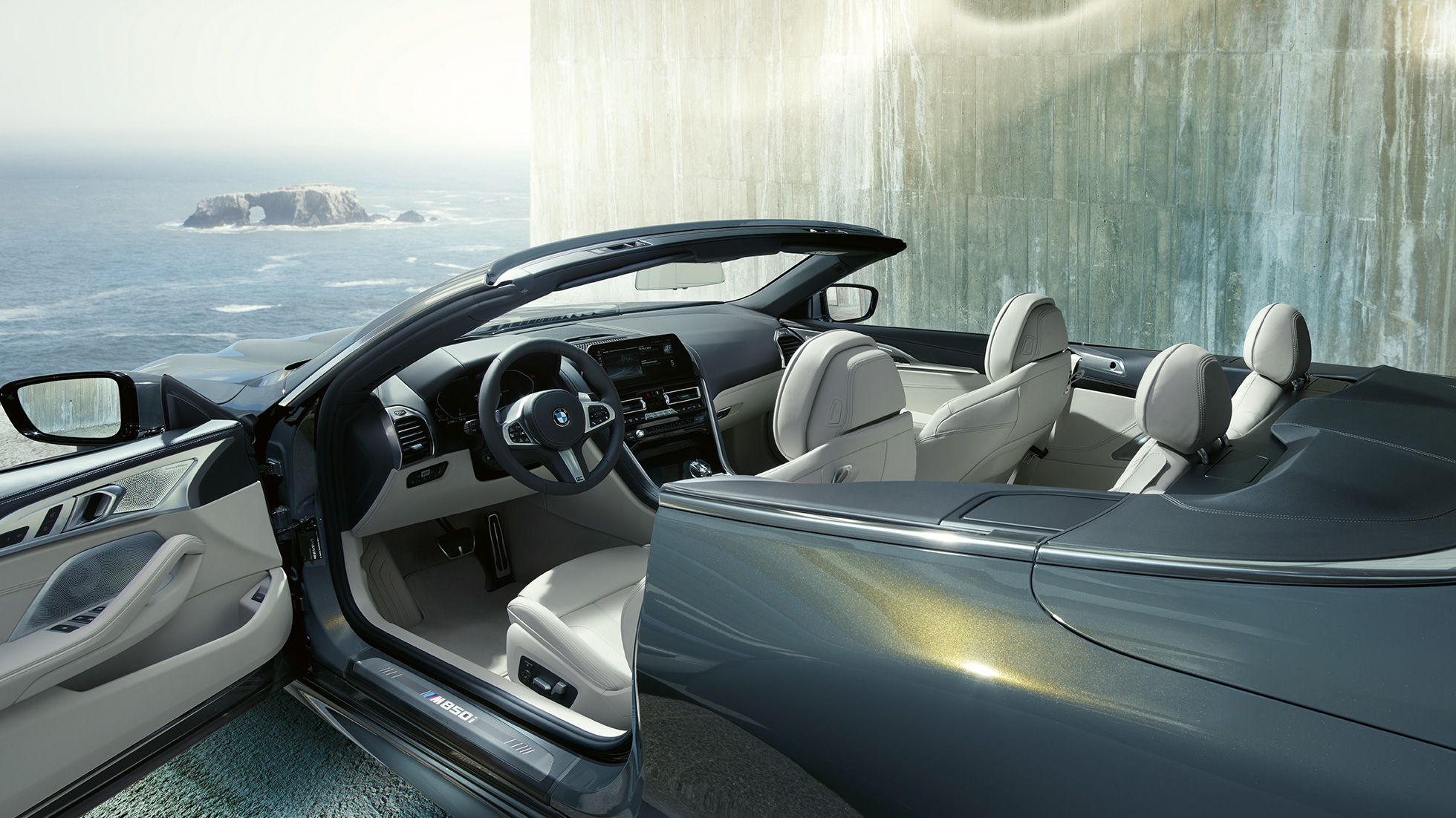 BMW M850i xDrive Cabrio, Interieur. BMW M850i xDrive Cabrio in Dravitgrau metallic mit geöffnetem Verdeck, Interieur mit M Lederlenkrad und BMW Individual Lederausstattung 'Merino' Elfenbeinweiß.