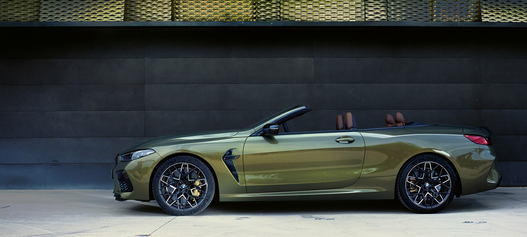 BMW M8 Competition Cabrio F91 LCI Facelift 2022 Seitenansicht stehend BMW M8 Competition Cabrio F91 LCI Facelift 2022 BMW Individual Brass metallic Seitenansicht stehend mit geöffneter Tür und weiblichem Model