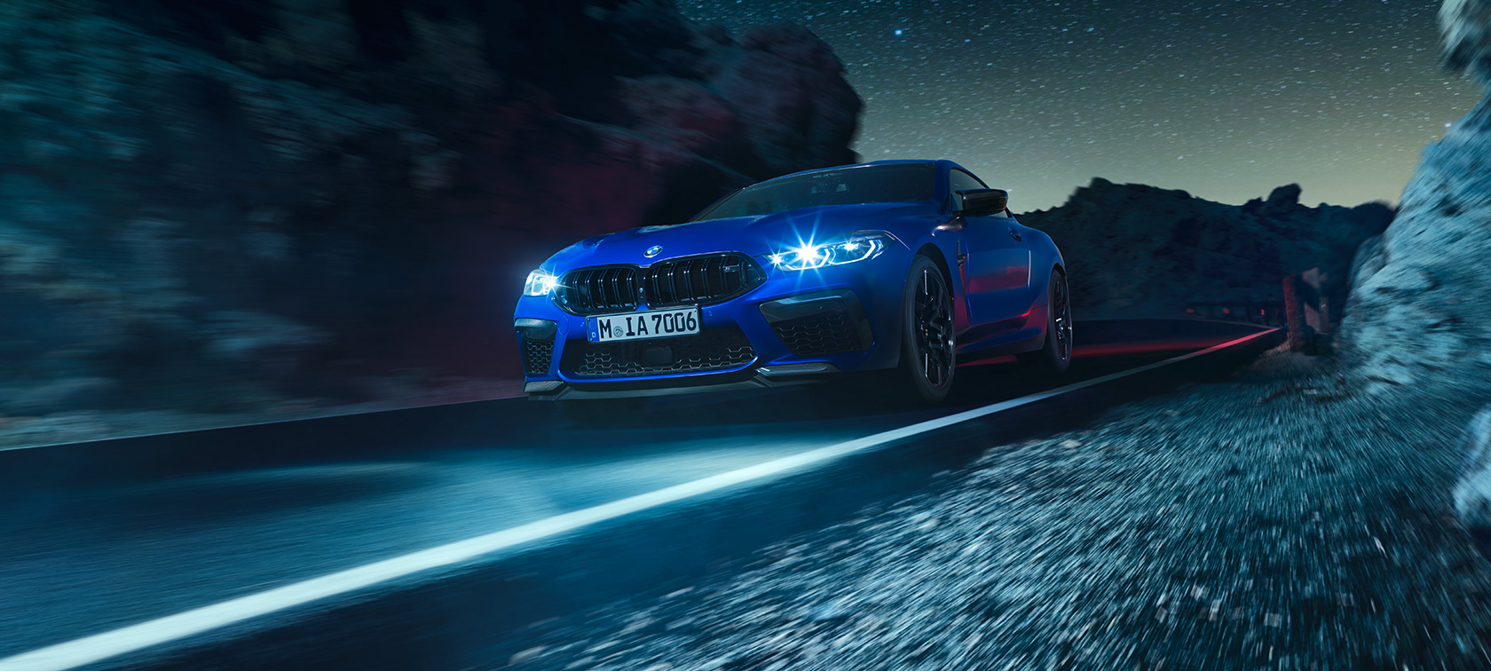 BMW M8 Competition Coupé, Dreiviertel-Frontansicht. Das BMW M8 Competition Coupé in Marina Bay Blau metallic, Dreiviertel-Frontansicht, fahrend bei Nacht.