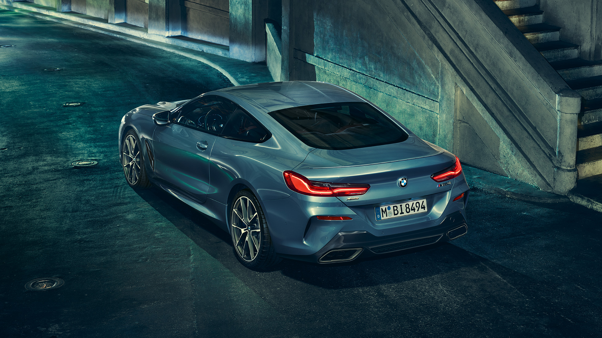 BMW M850i xDrive Coupé, Dreiviertel-Heckansicht links. BMW M850i xDrive Coupé in Barcelona Blau metallic, Dreiviertel-Heckansicht links, stehend bei Nacht.