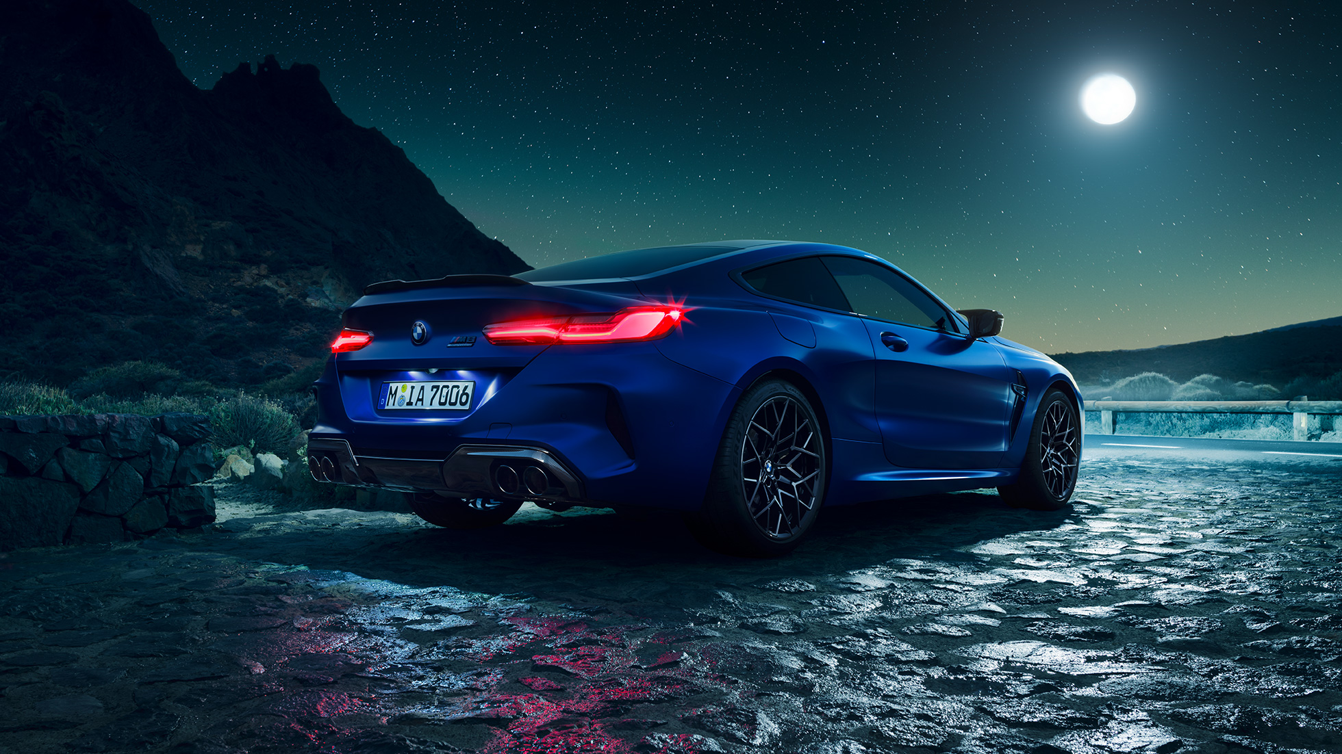 BMW M8 Competition Coupé, Dreiviertel-Heckansicht. BMW M8 Competition Coupé in Marina Bay Blau metallic mit strahlenden LED-Heckleuchten, stehende Dreiviertel-Heckansicht bei Vollmond.