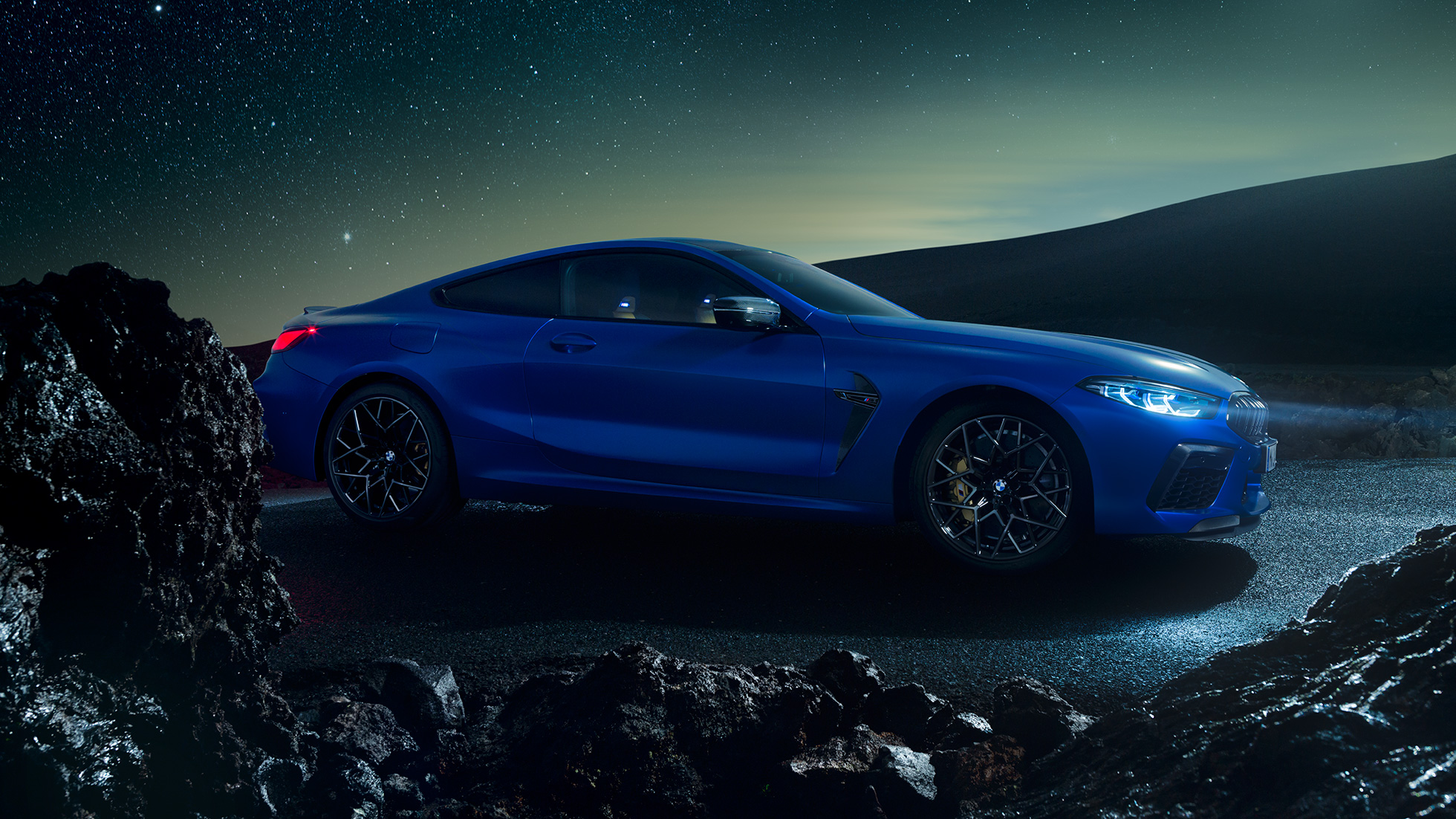 BMW M8 Competition Coupé, Dreiviertel-Seitenansicht. BMW M8 Competition Coupé in Marina Bay Blau metallic, stehende Dreiviertel-Seitenansicht bei Nacht.