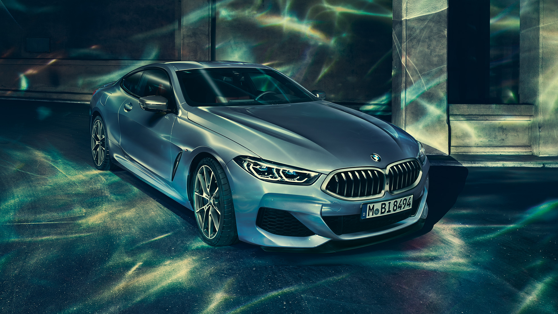 BMW M850i xDrive Coupé, Dreiviertel-Frontansicht links. BMW M850i xDrive Coupé in Barcelona Blau metallic, Dreiviertel-Frontansicht links, stehend vor Gebäude.