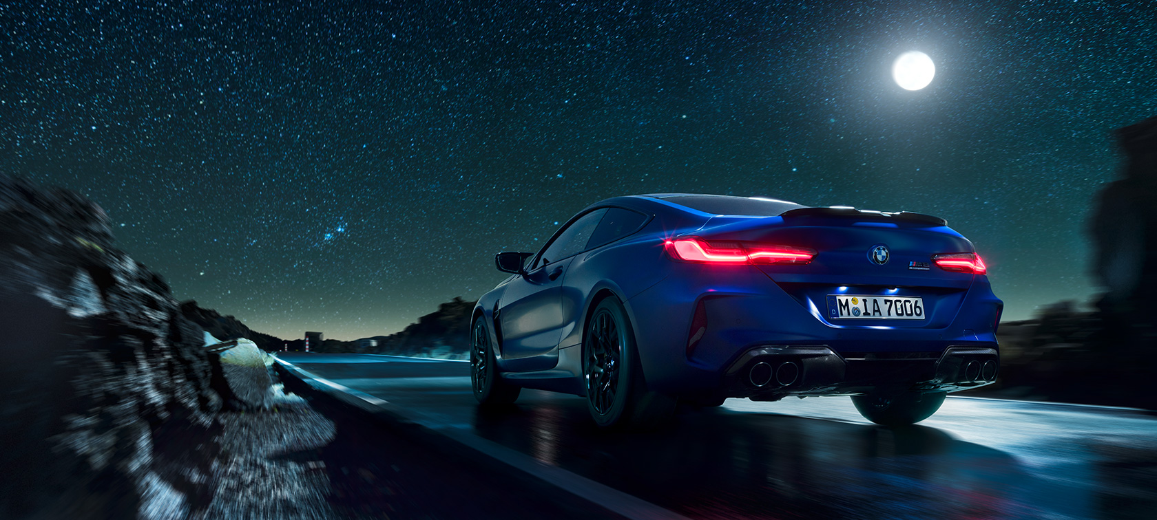 BMW M8 Competition Coupé, Heckansicht. BMW M8 Competition Coupé, Heckansicht, fahrend bei Nacht mit Vollmond.