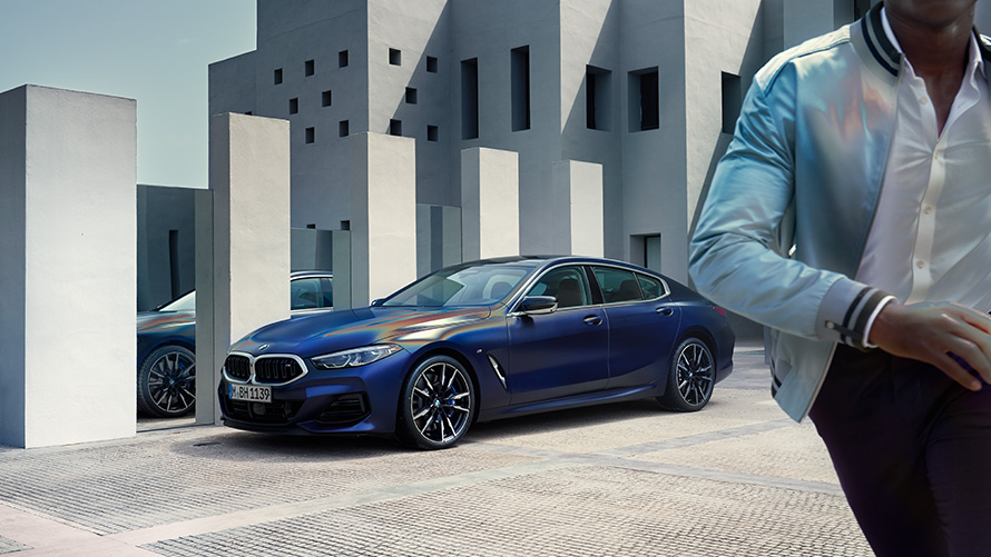 BMW M850i xDrive Gran Coupé G16 LCI Facelift 2022 BMW Individual Frozen Tansanitblau metallic Dreiviertel-Frontansicht stehend mit männlichem Model im Vordergrund