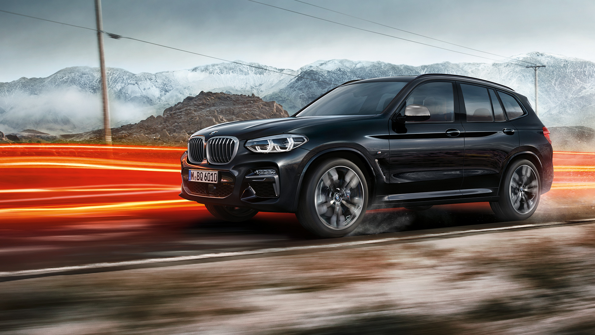 BMW X3 M40i und BMW X3 M40d, Seitenansicht. BMW X3 M40i und BMW X3 M40d in Saphierschwarz metallic, fahrend, Exterieur, Seitenansicht vor Berglandschaft mit Lichtstreifen.