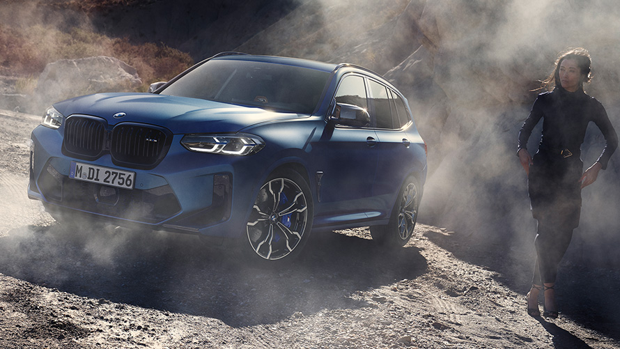 BMW X3 M Competition F97 LCI 2021 Dreiviertel-Frontansicht stehend in steinigem Gelände BMW X3 M Competition F97 LCI Facelift 2021 Frozen Marina Bay Blau metallic Dreiviertel-Frontansicht stehend in steinigem Gelände mit weiblichen Model