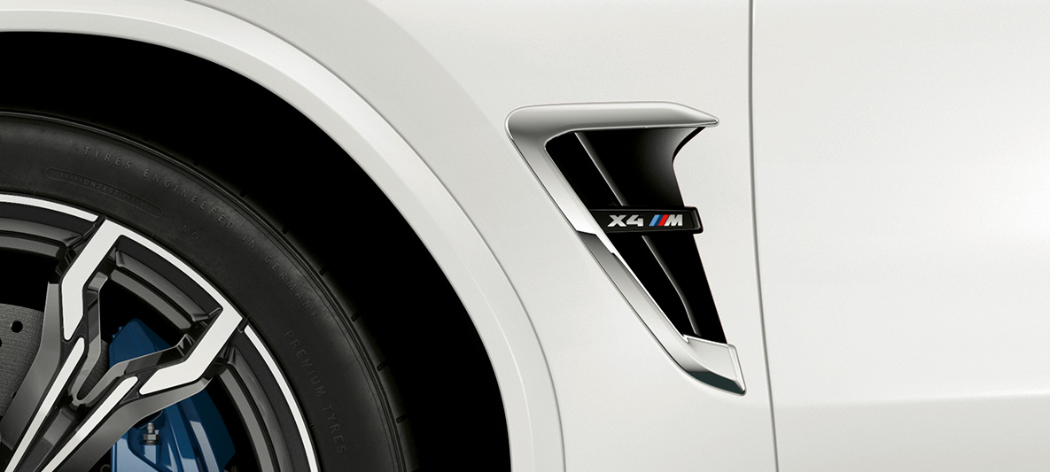 BMW X4 M, M Kieme. BMW X4 M in Alpinweiß, Exterieur, M Kieme mit Chrom-Highlights und Modellkennzeichnung.