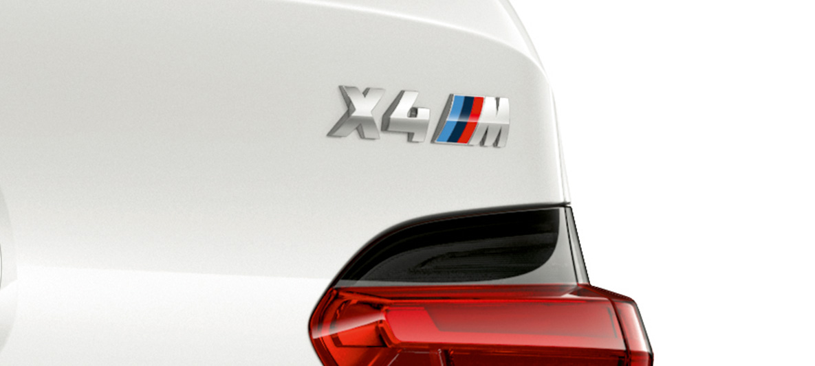 BMW X4 M, Modellkennzeichnung. BMW X4 M in Alpinweiß, Exterieur, Nahaufnahme Heck mit Modellkennzeichnung.