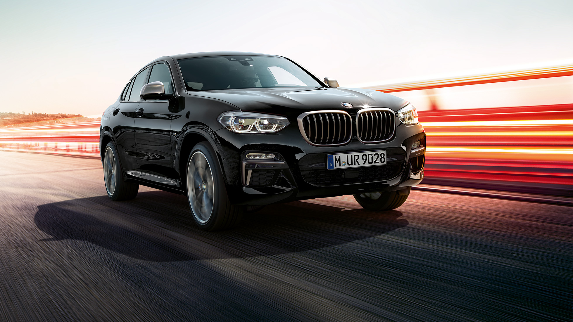 BMW X4 M40i und BMW X4 M40d, Dreiviertel-Frontansicht. BMW X4 M40i und BMW X4 M40d in Saphierschwarz metallic, Exterieur, Dreiviertel-Frontansicht links mit Lichtstreifen.