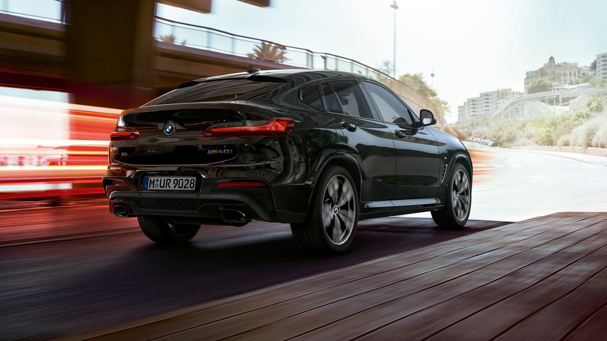 BMW X4 M40i, Dreiviertel-Heckansicht. BMW X4 M40i in Saphierschwarz metallic, Exterieur, Dreiviertel-Heckansicht rechts mit Lichtstreifen.
