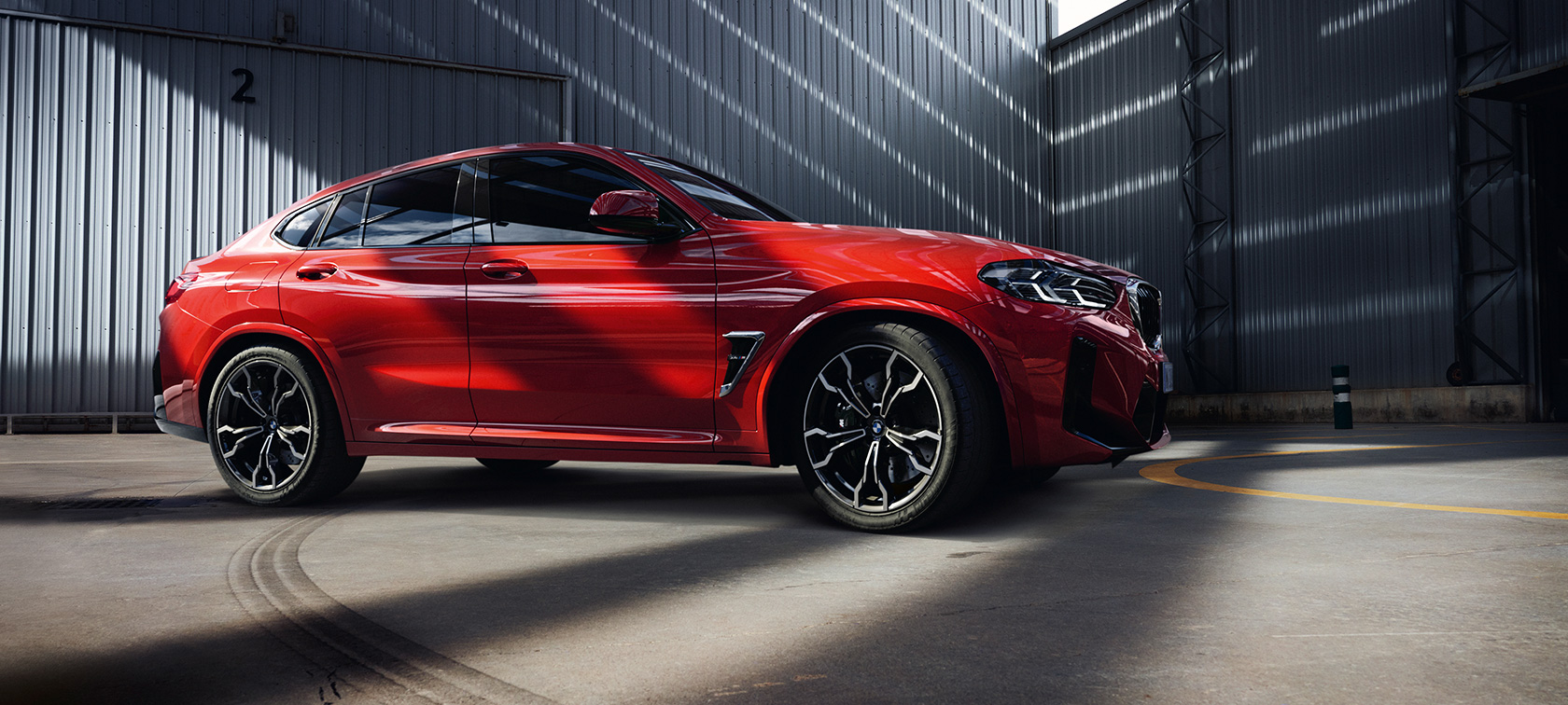 Dreiviertel-Frontansicht BMW X4 M F98 LCI Facelift 2021 BMW X4 M F98 LCI Facelift 2021 Toronto Rot metallic Dreiviertel-Frontansicht in Fabrikhalle