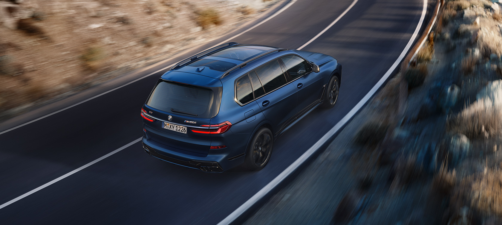 BMW X7 M60i xDrive G07 LCI Frozen Marina Bay Blue Dreiviertel-Heckansicht Vogelperspektive fahrend BMW X7 M60i xDrive G07 LCI Frozen Marina Bay Blue Dreiviertel-Heckansicht Vogelperspektive fahrend auf der Straße