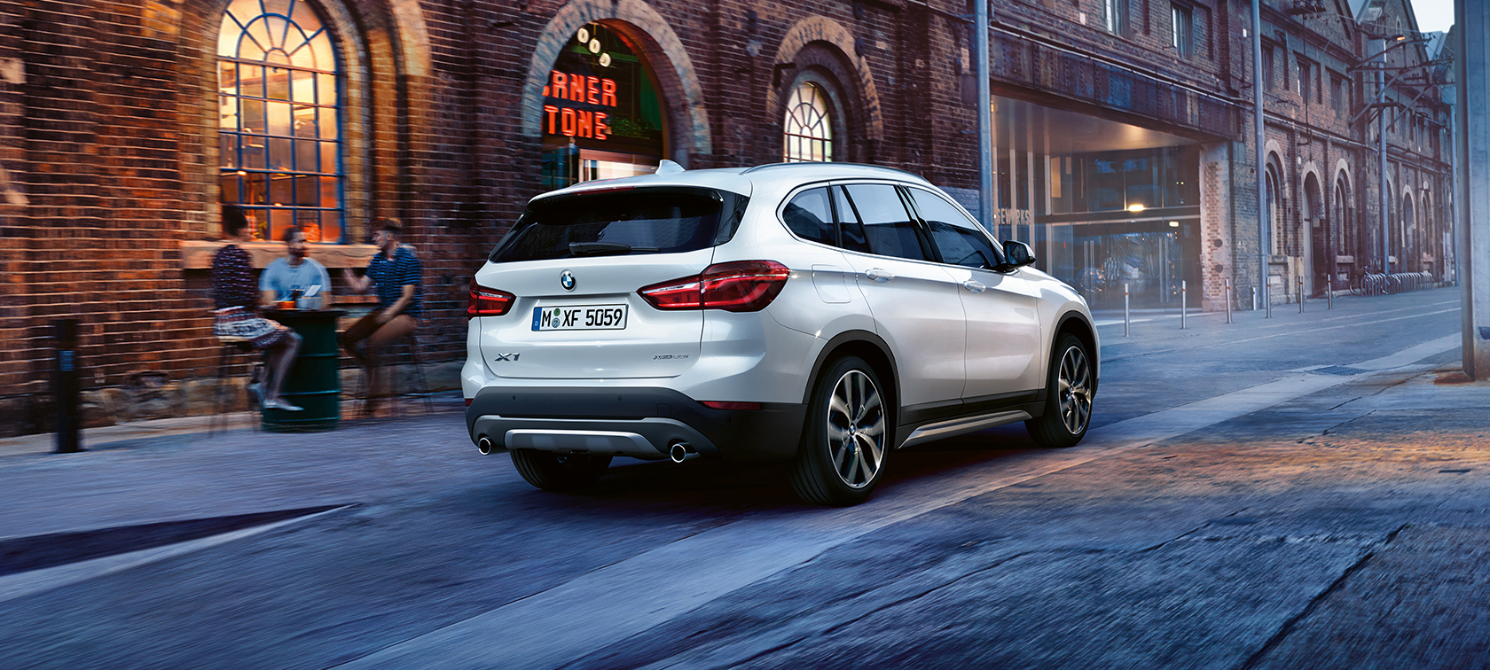 BMW X1 weiß auf der Straße - Rückansicht BMW X1 weiß auf der Straße - Rückansicht