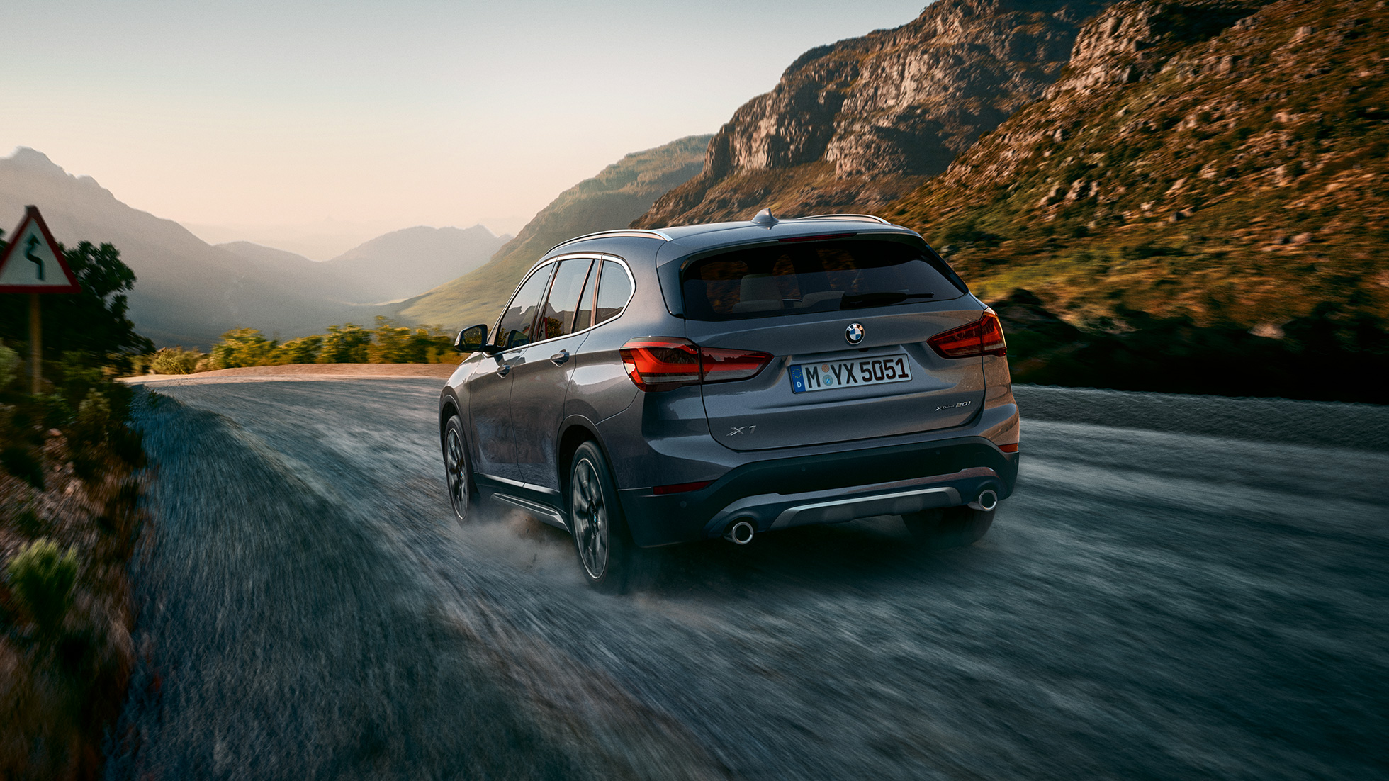 BMW X1, Dreiviertel-Heckansicht. BMW X1, Dreiviertel-Heckansicht fahrend vor Gebirgskulisse.