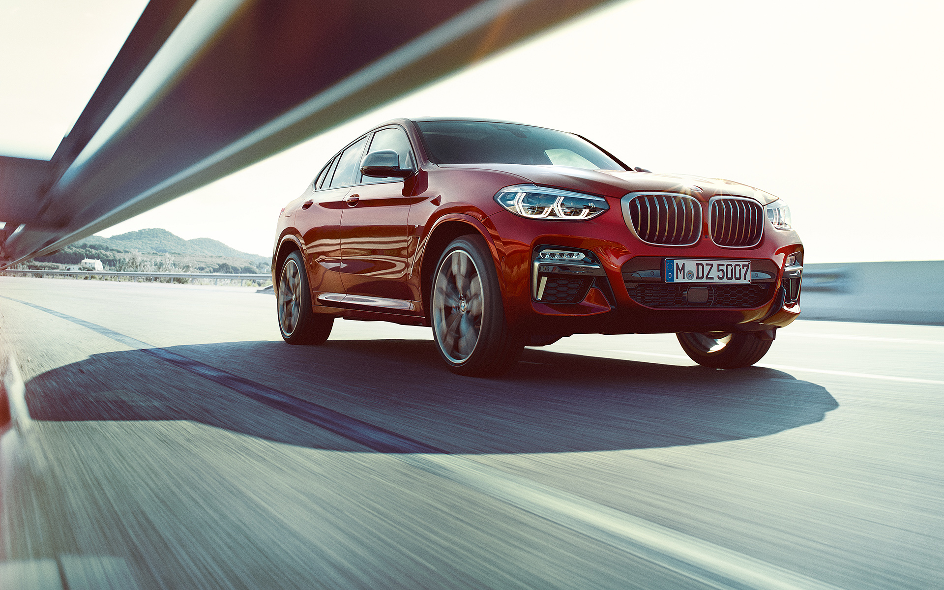 Fahrender BMW X4 rot auf der Straße - Vorderansicht Fahrender BMW X4 rot auf der Straße - Vorderansicht