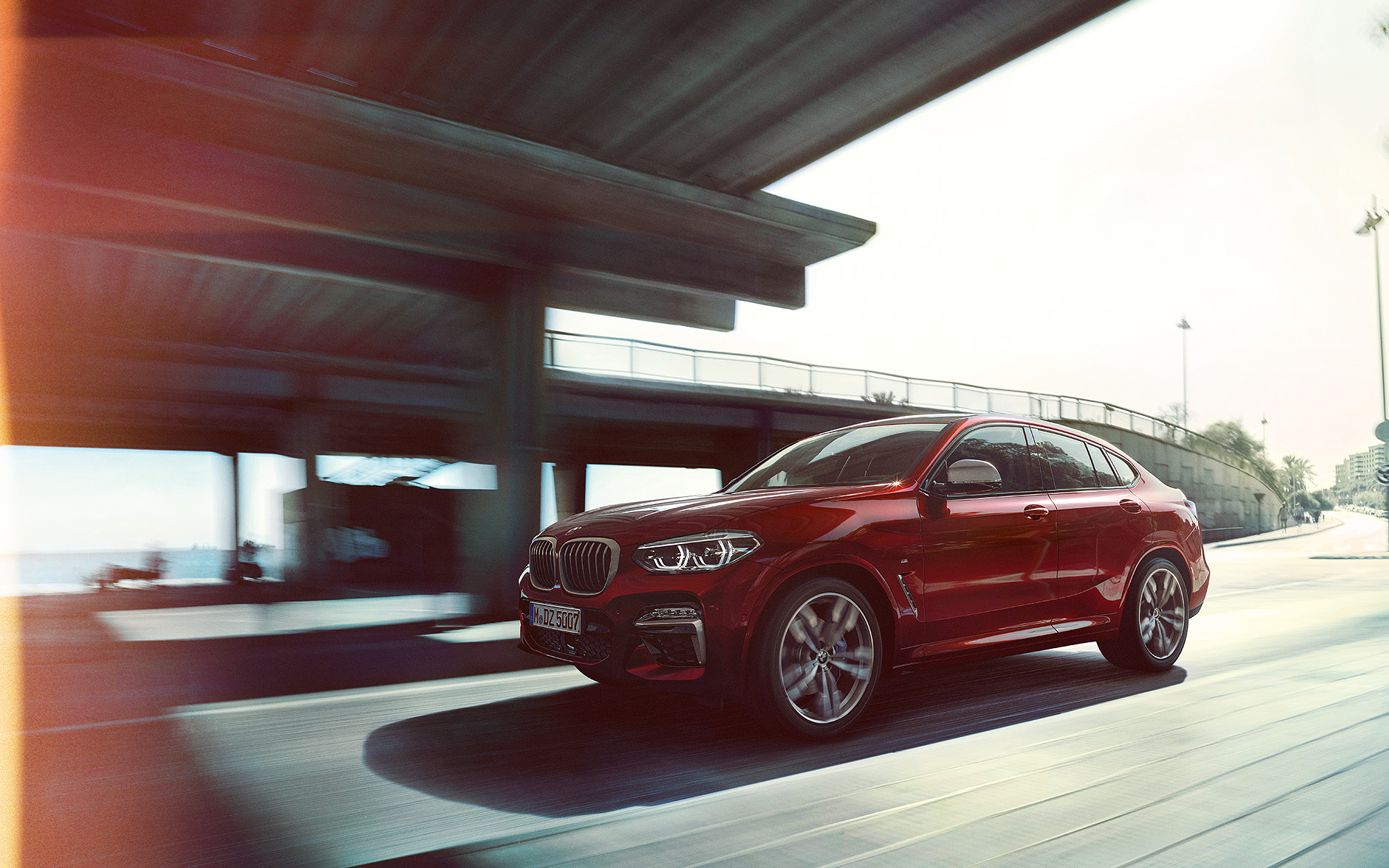 Fahrender BMW X4 rot auf der Straße - Seitenansicht Fahrender BMW X4 rot auf der Straße - Seitenansicht