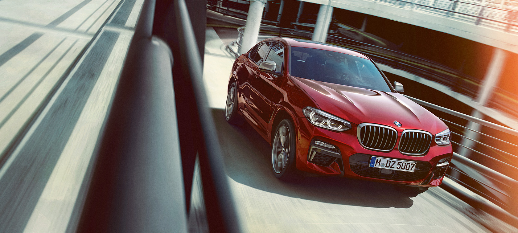 BMW X4 fahrend im Parkhaus BMW X4 G02 2018 Flamencorot Brillanteffekt Dreiviertel-Seitenansicht fahrend im Parkhaus