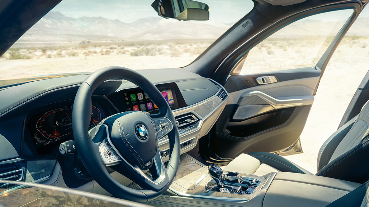 BMW X7 Interieur BMW X7 Interieur: Sicht von außen in die erste Sitzreihe mit Blick auf Lenkrad, Instrumentenkombination und Ledersitze