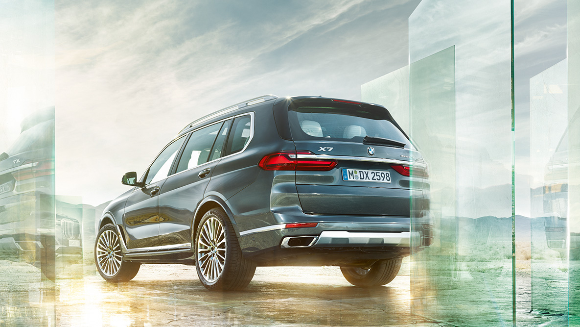 BMW X7 Fahrkomfort und Fahrdynamik BMW X7 aus der dreiviertel Heckansicht vor abstraktem Hintergrund